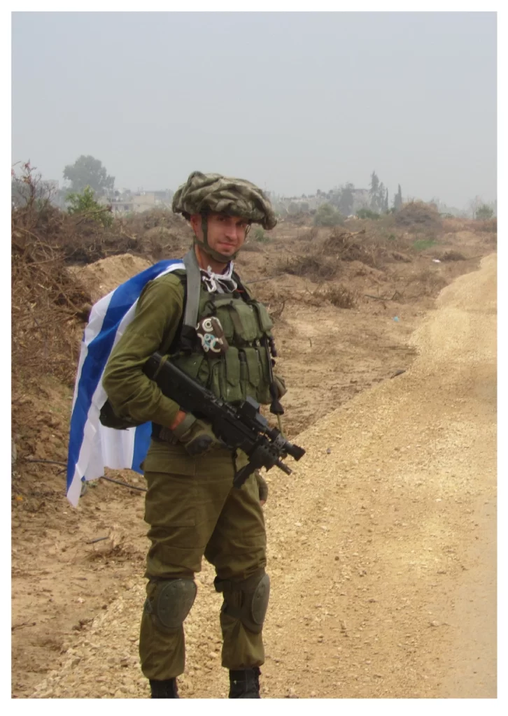 חייל מילואים בשובו מהתמרון הגדול עומד עם דגל ישראל על גבו